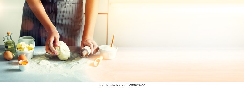 Female hands kneading dough, baking background. Cooking ingredients - eggs, flour, sugar, butter, milk, rolling pin on white style kitchen. Copy space. Banner.