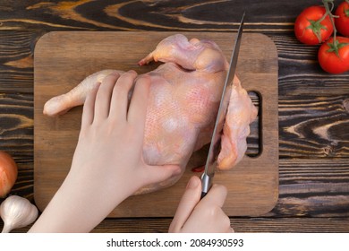 Female Hands With A Knife Cut Homemade Chicken. Hand Cuts Off A Chicken Wing