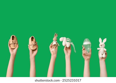 Female hands with knitted toys, baby booties and bottle on green background - Powered by Shutterstock