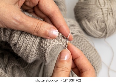 Female Hands Knitting Holding Knitting Needles With A Big Ball Of Wool In The Background 