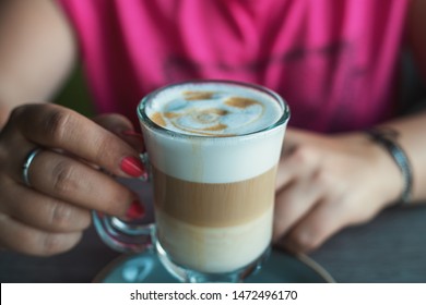 Female hands with latte coffee in cafe, close up with selective focus