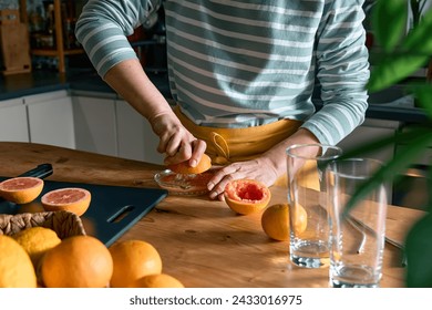 Female hands making homemade grapefruit juice with hand citrus juicer. Anonymous woman preparing fresh grapefruit juice in the kitchen. - Powered by Shutterstock