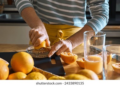 Female hands making homemade grapefruit juice with hand citrus juicer. Anonymous woman preparing fresh grapefruit juice in the kitchen. - Powered by Shutterstock