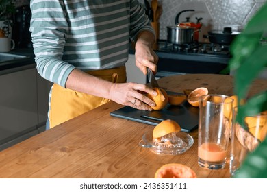 Female hands making homemade grapefruit juice with hand citrus juicer. Anonymous woman cutting ripe grapefruit in half for preparing fresh grapefruit juice. - Powered by Shutterstock