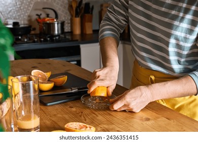 Female hands making homemade grapefruit juice with hand citrus juicer. Anonymous woman preparing fresh grapefruit juice in the kitchen. - Powered by Shutterstock