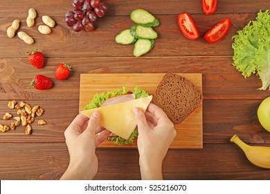 Female Hands Making Tasty Sandwich On Wooden Board