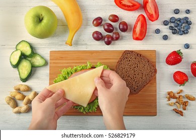 Female Hands Making Tasty Sandwich On Wooden Board