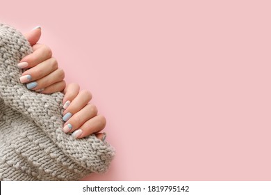 Female hands manicure close up view with knitted sweater on pink background. Trendy Geometric Nail Art Manicure. Manicure salon banner concept
