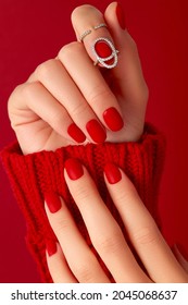 Female hands with manicure in sweater. Red matt nail design