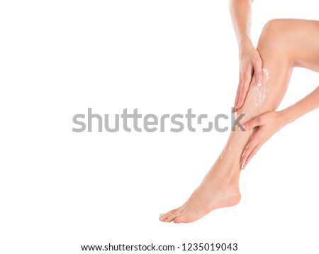 Female hands massage her leg with body lotion, close up, isolated on white. Applying cream is on the skin.