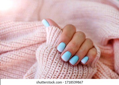 Female hands matte blue gradient manicure close up view pink knitted sweater background  Nail painting effects 