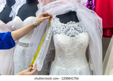 Female hands with measuring tape and wedding dress