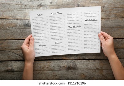 Female Hands With Menu On Wooden Table