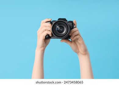 Female hands with modern camera on blue background