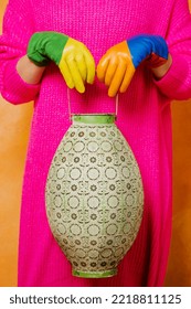 Female Hands In Multi-colored Leather Gloves Hold A Vintage Vase