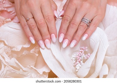 Female hands with ombre manicure nails, pink gel polish, on paper flowers background