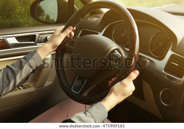 Female hands on driving\
wheel