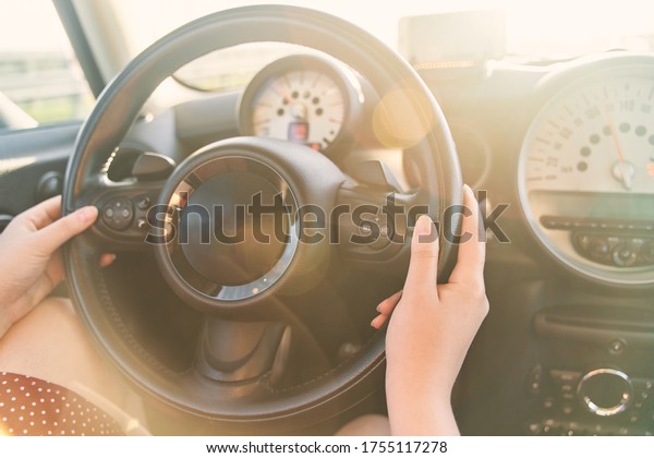  Female hands on the steering wheel of a car
while driving.