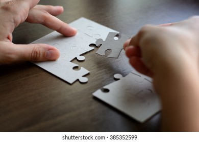 Female hands on a wooden office desk pick puzzle - Shutterstock ID 385352599