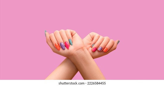 Manos femeninas: uno con un largo y colorido diseño de uñas y otro con diseño de clavos cortos. Manicura de esmalte de uñas brillante: morado, verde, rosa y naranja. Manos de modelo hembra con manicura colorida perfecta sobre p
