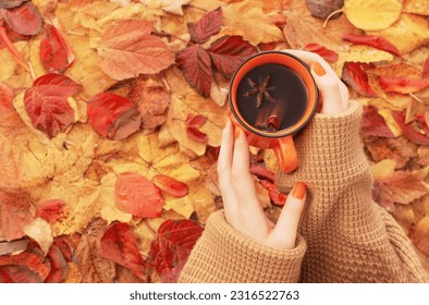 female hands with orange cup of coffee on background autumn leaves - Powered by Shutterstock