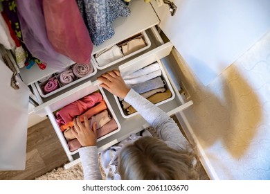 Female hands organizing storage of underwear socks t shirts use Marie Kondo's method. Perfectionist Teenage girl. Children's wardrobe