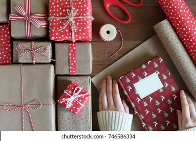 Female hands packs the Christmas book into paper