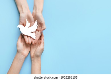 Female hands with paper dove on color background. International Day of Peace - Shutterstock ID 1928286155