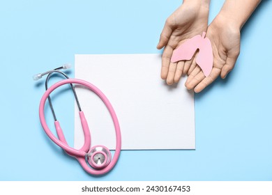 Female hands with paper lungs, stethoscope and blank card on blue background - Powered by Shutterstock