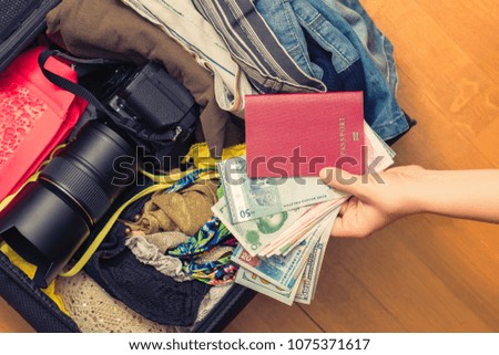 Female hands with passport Asian money and American hundred dollar bills. Suitcase with things on the floor. Choosing and exchange currency. Travel concept 
