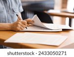 Female hands with pen signing documents, business papers on wooden table. Sign documents, loans, rent, work contracts, woman working in office, accountant, bank employee