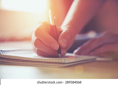 female hands with pen writing on notebook