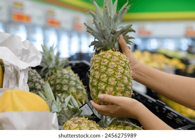 Female hands picking up a pineapple from a supermarket shelf. - Powered by Shutterstock