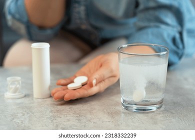Female hands with pills on background of water glass with effervescent tablet. Soluble drug.Take medicine, vitamins.