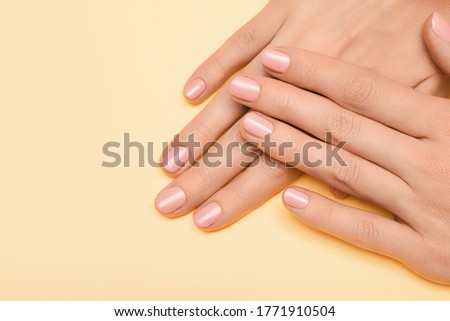 Female hands with pink nail design. Pink nail polish manicure. Female hands on pale orange background.