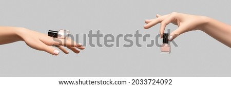 Female hands with pink nail design. Pink nail polish manicure. Woman hands hold pink nail polish bottle on beige background. Copy space.