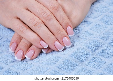 Female Hands With Pink Nails On A Blue Towel. Art Painting Of Nails. Care For Sensuality Female Hands. Perfect Artificial Fingernails Of Adult Woman. Shallow Depth Of Field