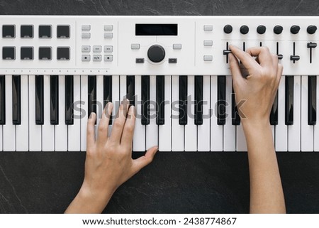 Female hands play on a white midi keyboard, a musician plays a synthesizer, top view. Learning to play the piano.