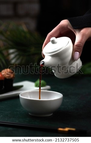 Female hands pouring soy sauce into a bowl, Asian cuisine