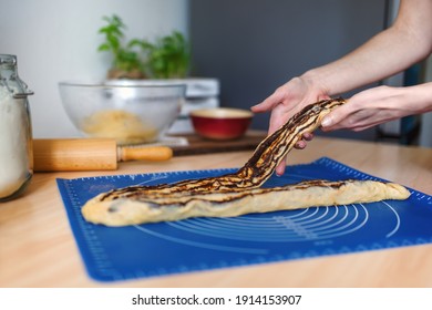 Female hands preparing a chocolate babka - traditional jewish bread-like cake swirled with chocolate or cinnamon and often topped with nuggets of cinnamon-sugar streusel.