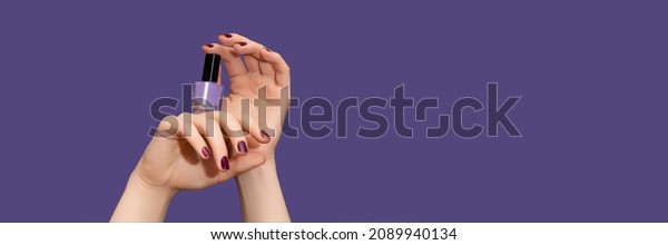 Female\
hands with purple nail design. Glitter purple nail polish manicure.\
Female hands hold purple nail polish on purple background. Copy\
space. Banner ad template. Advertising\
banner.
