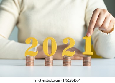 Female Hands Putting Gold Wooden Number 2021 On Stack Of Coins. Tax Payment, Investment And Banking.2021 New Year Saving Money And Financial Planning Concept. 