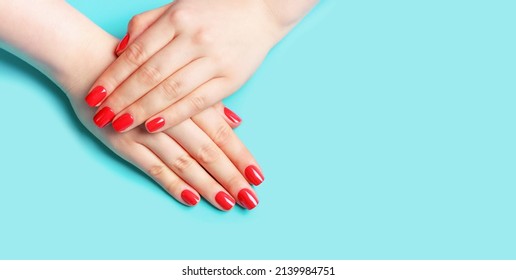 Female Hands With Red Manicure On Blue Background, Copy Space.