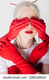 Female Hands In Red Paint Covering Eyes Of Albino Model Isolated On White