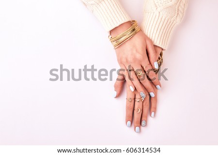 Female hands in rings and bracelets on a white background. Beautiful blue manicure. Many different costume jewelery.