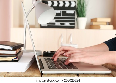 Female Hands Of Scriptwriter Working On Laptop At Desk On Cupboard Background