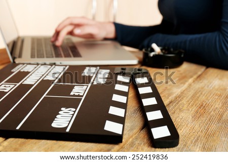 Female hands of scriptwriter working on laptop at desk on cupboard background