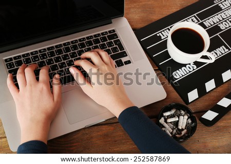 Female hands of scriptwriter working on laptop at wooden desk background