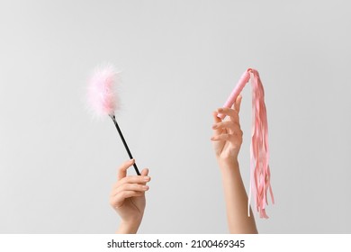 Female hands with sex toys on light background