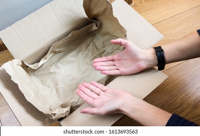 Female Hands Show An Empty Cardboard Box Only With Packaging Paper. E-commerce Fraud, Where Is My Order, Concept Image. Selective Focus, Close-up.